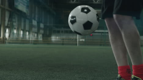 Beine-Eines-Fußballsportlers,-Der-Auf-Dem-Hallenfeld-Mit-Dem-Ball-Jongliert